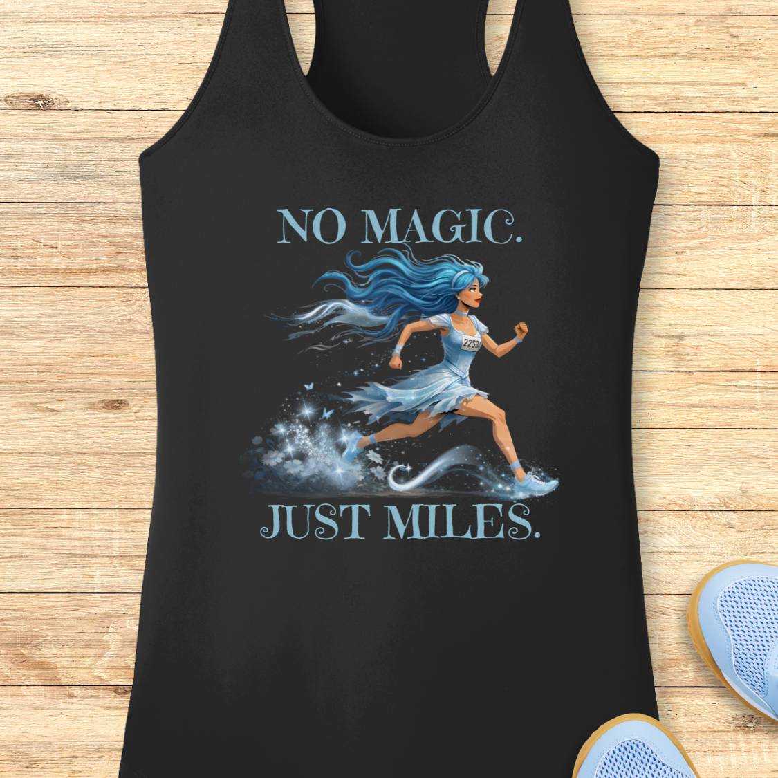 A black racerback tank top laid flat on a light wood background, featuring a graphic of a blue-haired woman running with the text 'NO MAGIC. JUST MILES.