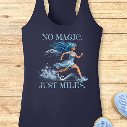 A navy blue racerback tank top laid flat on a light wood background, featuring a graphic of a running woman with blue hair and the text 'NO MAGIC. JUST MILES.