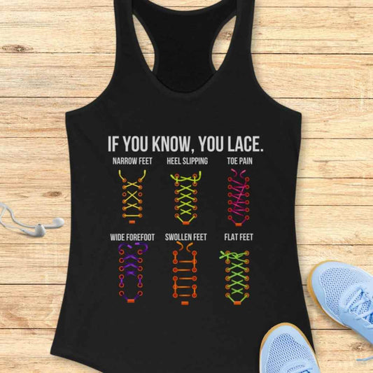 Graphic print on a black tank top with text 'IF YOU KNOW, YOU LACE' illustrating six distinct, colorful shoelace patterns like yellow for narrow feet and pink for toe pain all displayed on a wooden surface next to blue running shoes