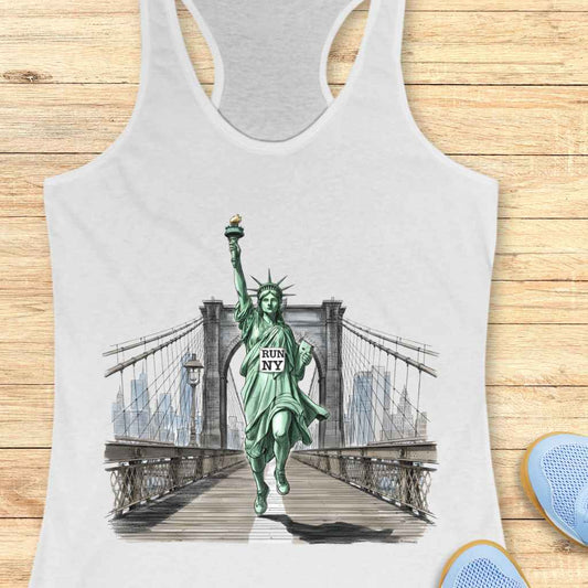 Graphic design of a green Statue of Liberty running in athletic shoes, holding a yellow torch and a "RUN NY" tablet, depicted on the Brooklyn Bridge with the New York City skyline in the background, featured on a white racerback tank top with blue athletic sneakers partly visible