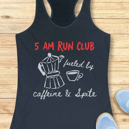 Printed navy blue racerback tank top on a light wooden surface features red text 5 AM RUN CLUB, a white Moka pot with coffee cup, and fueled by caffeine & Spite in white script, with light blue running shoes visible nearby