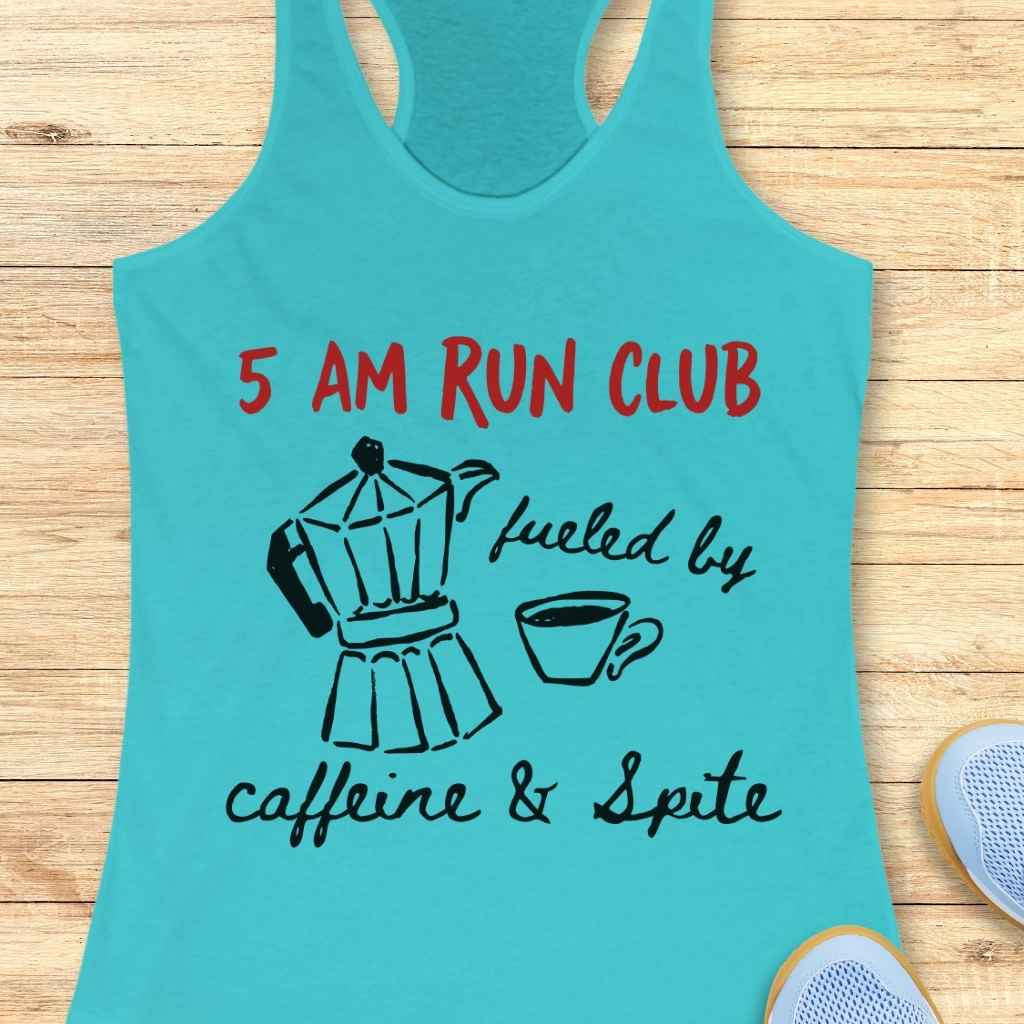A turquoise racerback tank top features red text 5 AM RUN CLUB above black line art graphics of a moka pot and a coffee cup with the handwritten phrase fueled by caffeine & Spite displayed on a light wooden background with parts of light blue running shoes visible