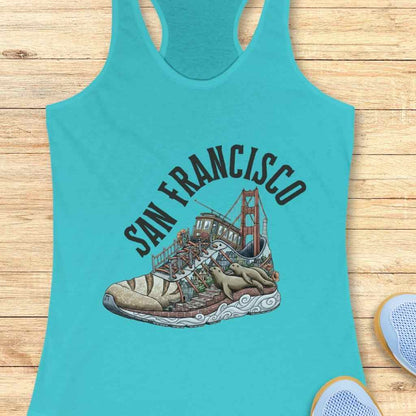 Graphic print on a teal tank top depicting a San Francisco cityscape within a running shoe, showcasing the Golden Gate Bridge, a cable car, Lombard Street-like steps, and two lounging sea lions on the sole, with 'SAN FRANCISCO' text arching above