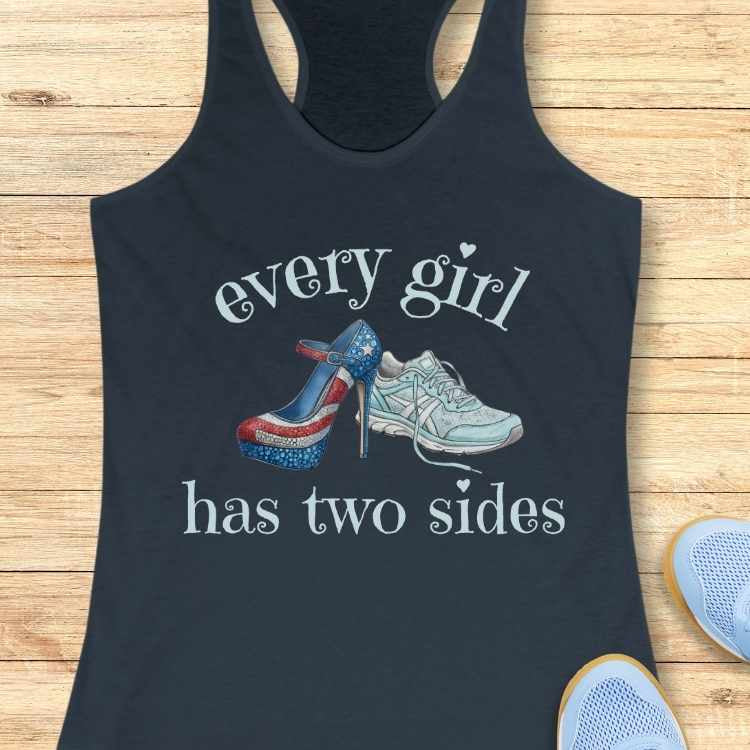 Black tank top with graphic of high heels and sneakers and text 'every girl has two sides' on a wooden surface.