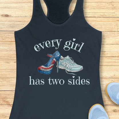 Black tank top with graphic of high heels and sneakers and text 'every girl has two sides' on a wooden surface.
