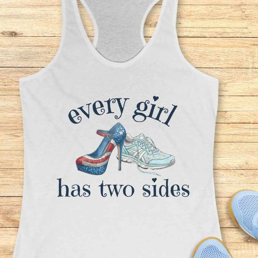 white tank top with high-heeled shoes and sneakers graphic and text 'every girl has two sides' on a wooden surface.