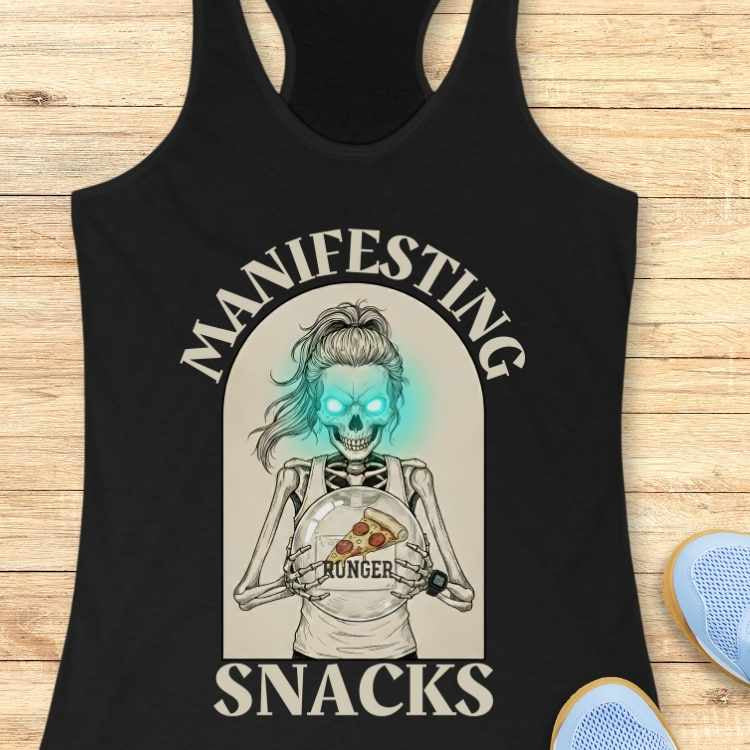 Black tank top with a graphic design of a skeleton holding a pizza and text 'Manifesting Snacks' on a wooden surface.