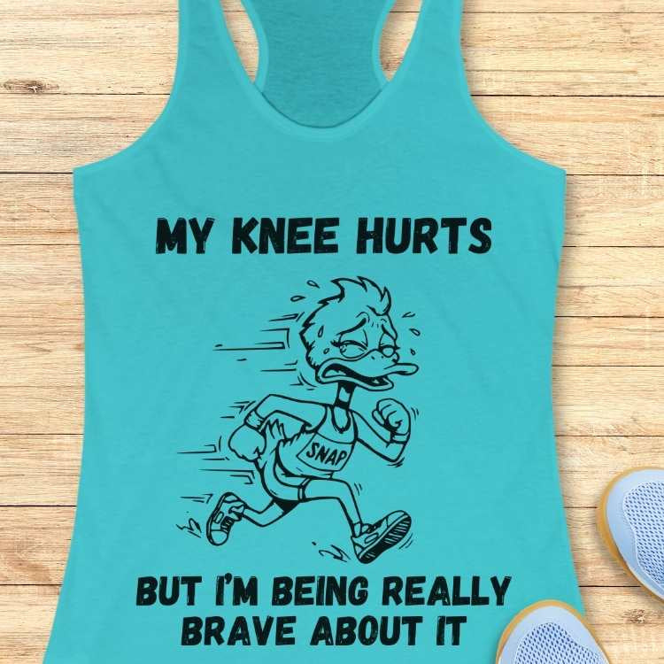 A bright turquoise tank top shirt featuring a black line art cartoon of a sweating, grimacing duck wearing a 'SNAP' running bib, with bold text above reading 'MY KNEE HURTS' and below 'BUT I'M BEING REALLY BRAVE ABOUT IT'