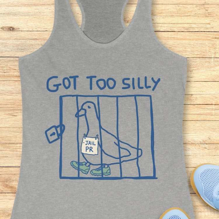 Grey women's racerback tank top featuring a blue line art cartoon of a pigeon wearing green sneakers and a 'JAIL PR' sign inside a cage, with 'GOT TOO SILLY' text above, displayed on a wooden background alongside a partially visible light blue sneaker