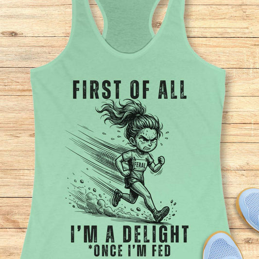 Mint green tank top with a graphic of a running girl and text first  of all I'm a delight , once I'm fed, on a wooden surface