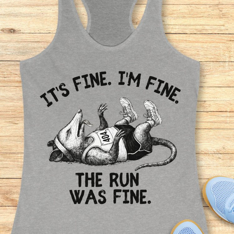 Gray tank top with possum
 graphic and text on a wooden surface