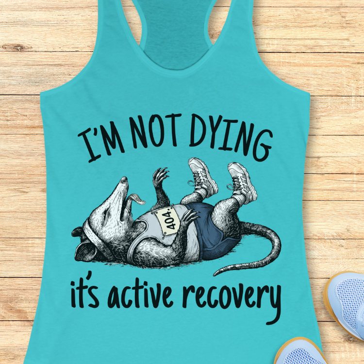 Turquoise tank top with possum graphic and text on a wooden surface