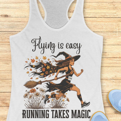 Tank top with a graphic of a witch running with a broom and text 'Flying is easy, running takes magic' on a wooden surface.