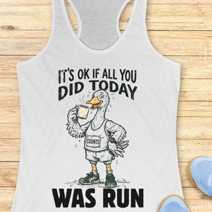 white tank top with a graphic of a duck and text "it's ok if all you did today was run" on a wooden surface