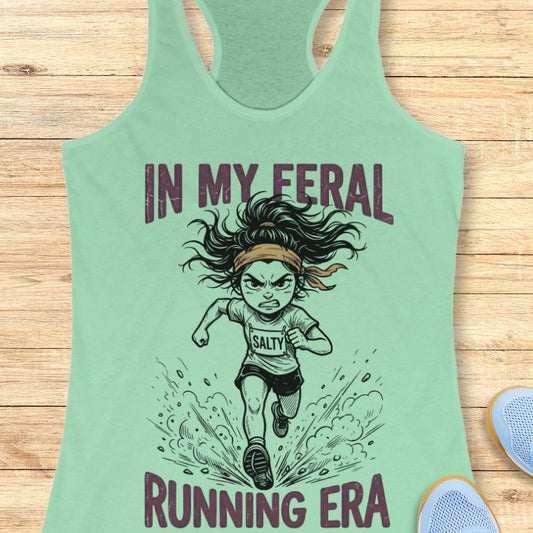 Mint green tank top with graphic design and text "in my feral running era" on a wooden surface