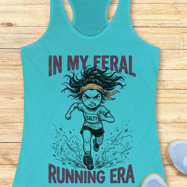 Turquoise tank top with graphic design and text Mint green tank top with graphic design and text "in my feral running era" on a wooden surface 