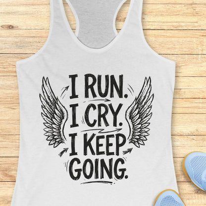 Gray tank top with motivational quote "I run. I cry. I keep going." and wings on a wooden surface