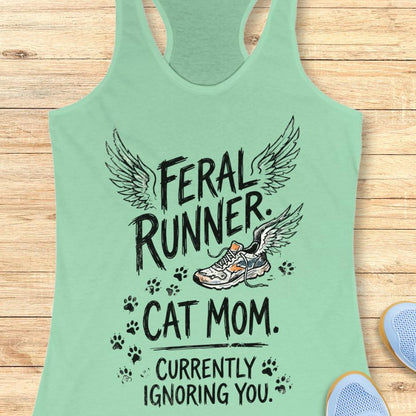 mint tank top with the text "feral runner. cat mom. currently ignoring you." on a wooden background