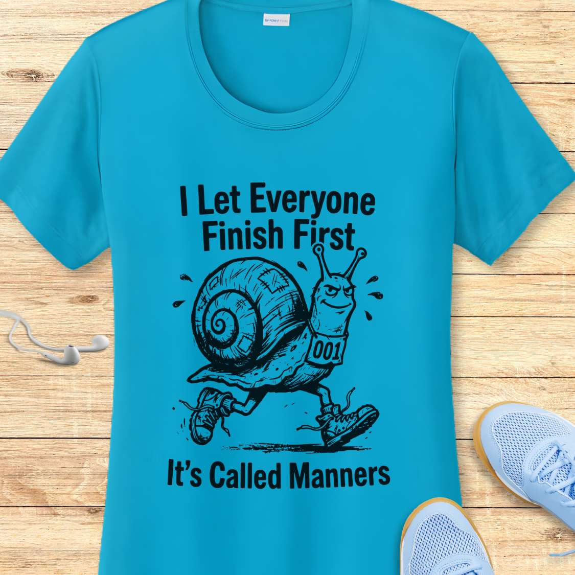 Blue t-shirt with a snail graphic and text on a wooden surface