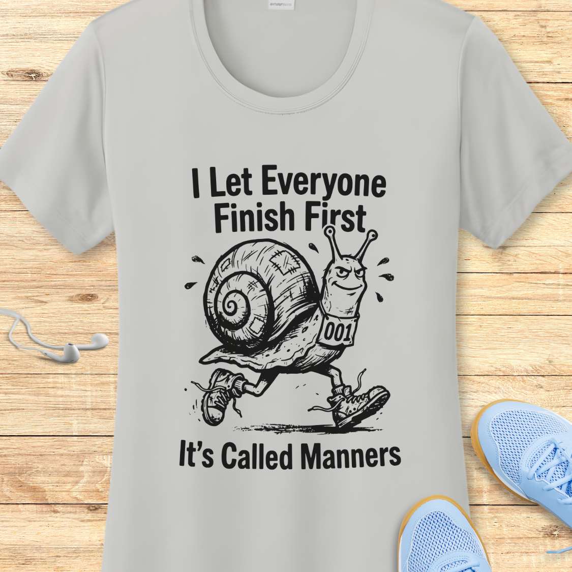 Gray t-shirt with a snail graphic and text on a wooden surface