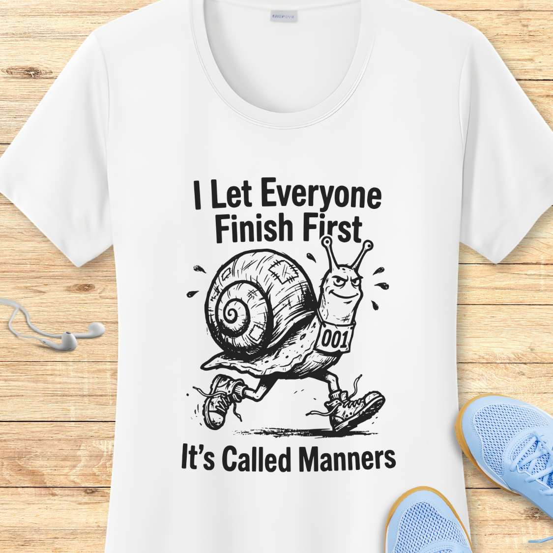 White t-shirt with a snail graphic and text on a wooden surface