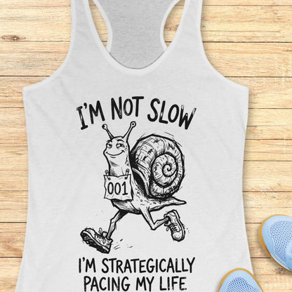 white tank top with a running snail and text - I'm not slow I'm strategically pacing my life on a wooden background