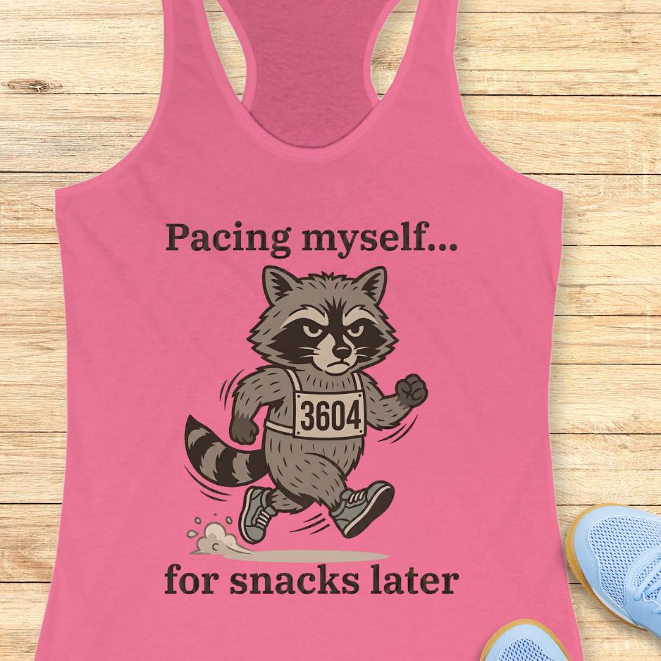 pink tank top with a running raccoon and text "pacing myself...for snacks later" on a wooden background