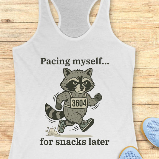 white tank top with a running raccoon and text "pacing myself...for snacks later" on a wooden background