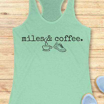 Mint green tank top with 'miles & coffee' text on a wooden surface