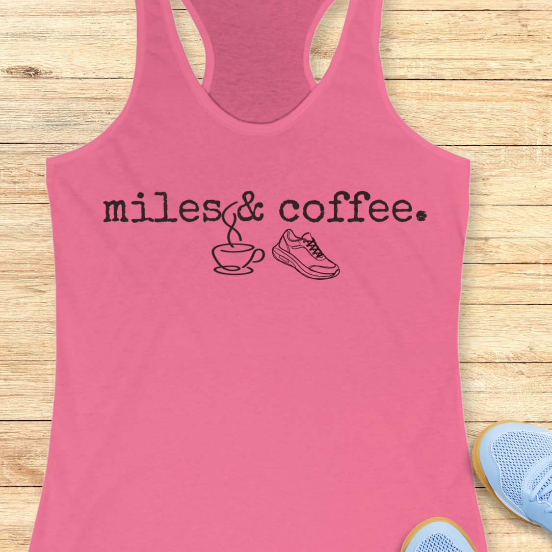 Pink tank top with 'miles & coffee' text on a wooden surface