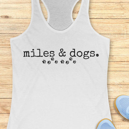 white tank top with 'miles & dogs.' text on a wooden surface