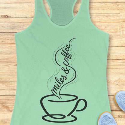 Mint green tank top with a coffee cup design and 'miles & coffee' text on a wooden surface.