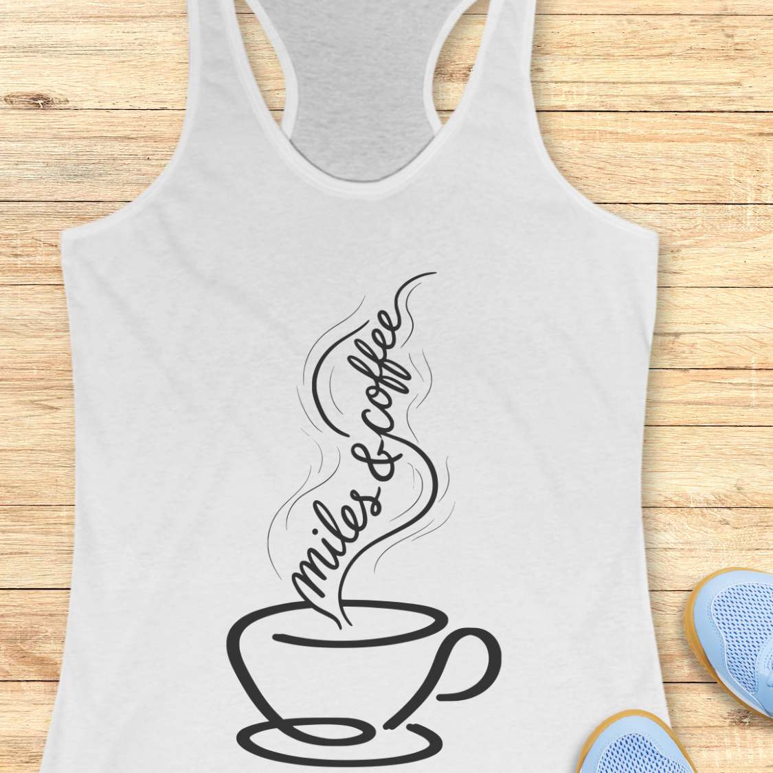 White tank top with a coffee cup and text miles and coffee design on a wooden surface