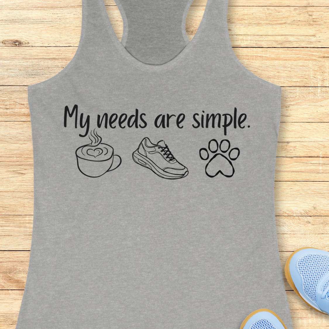 Gray tank top with text My needs are simple, and graphics on a wooden surface