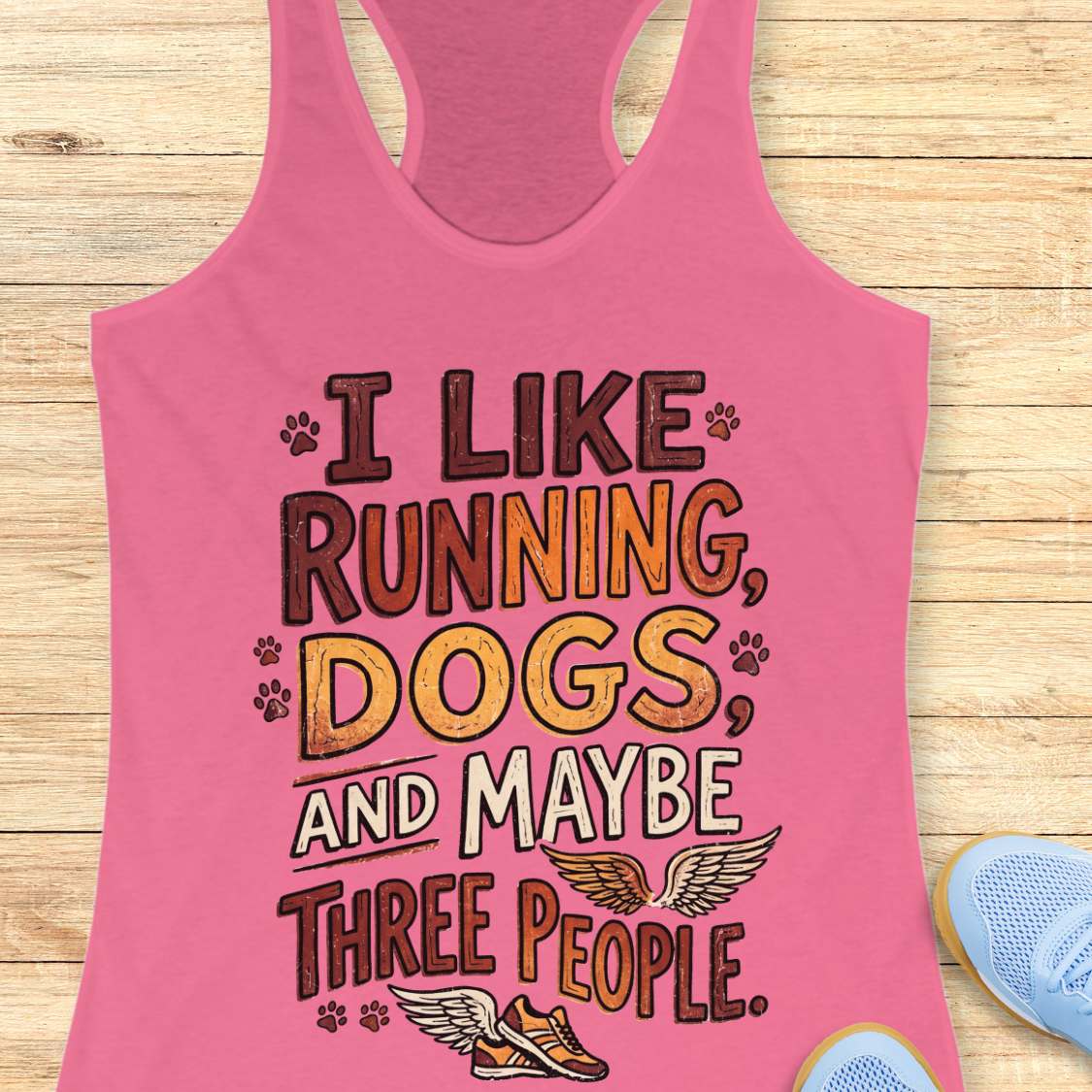 Pink tank top with text 'I like running, dogs, and maybe three people' on a wooden surface.