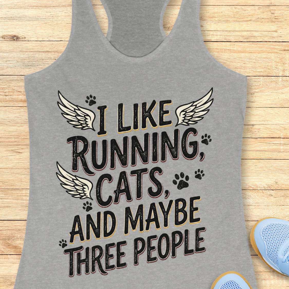 Gray tank top with text 'I like running, cats, and maybe three people' on a wooden surface