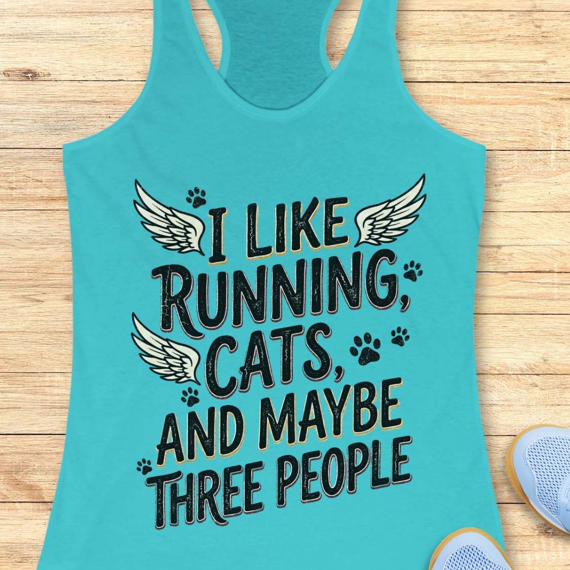 Turquoise tank top with text 'I like running, cats, and maybe three people' on a wooden surface.