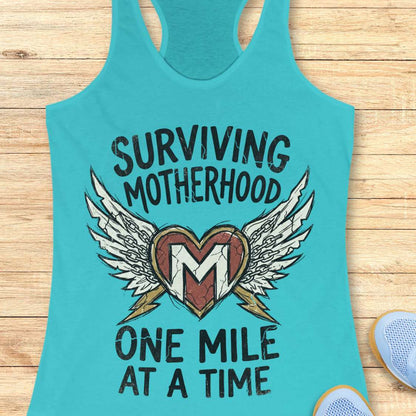 Turquoise tank top with 'Surviving Motherhood One Mile at a Time' text and heart design on a wooden surface.