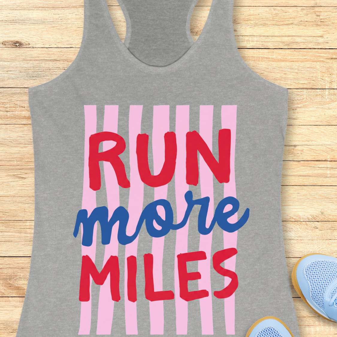 Gray tank top with 'RUN more MILES' text on a wooden surface