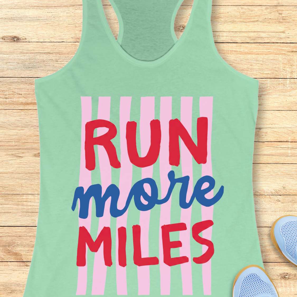 Green tank top with 'RUN more MILES' text on a wooden surface