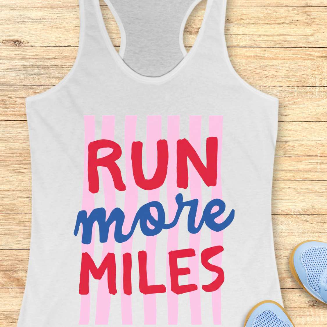White tank top with 'RUN more MILES' text on a wooden surface