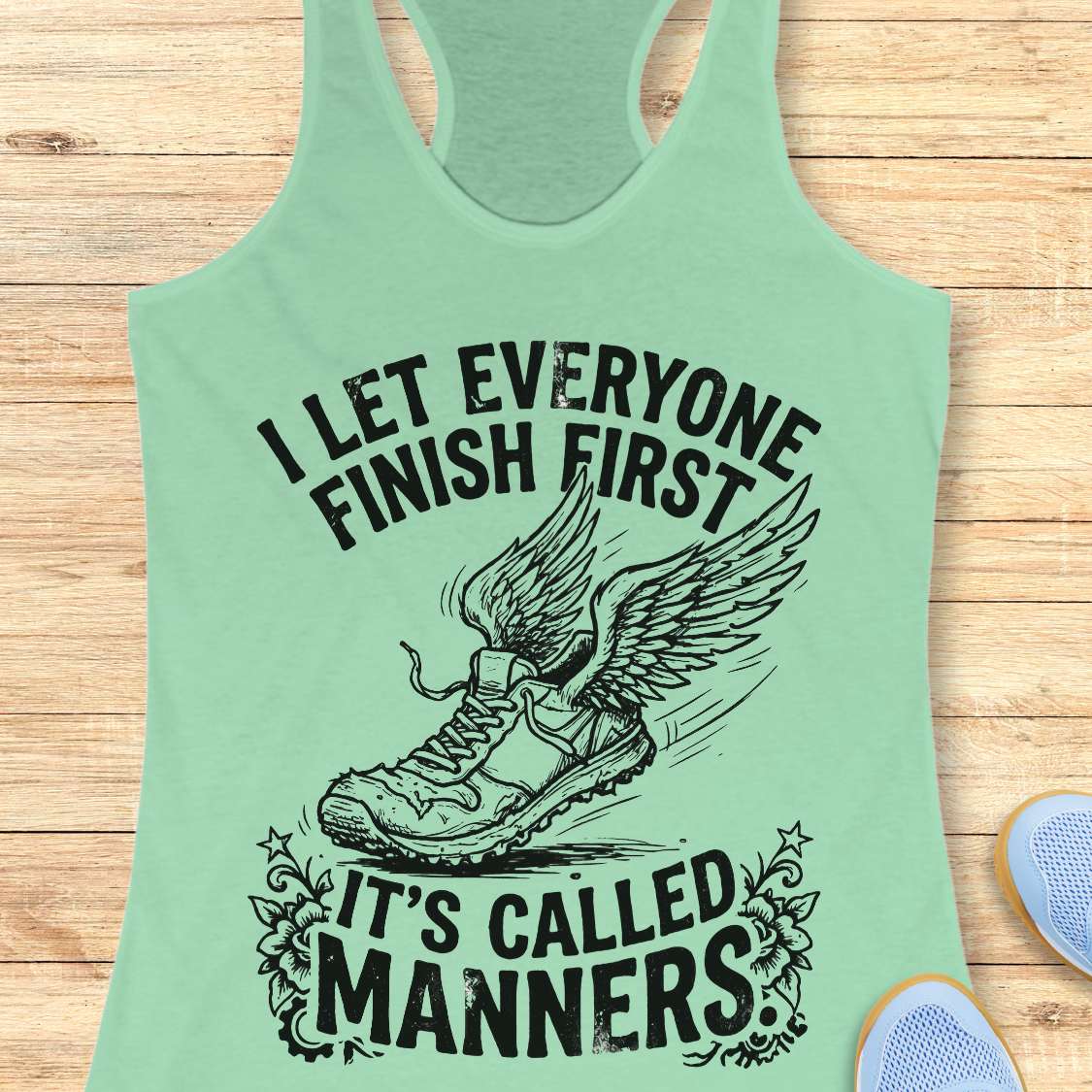 Mint green tank top with black text and graphic on a wooden surface