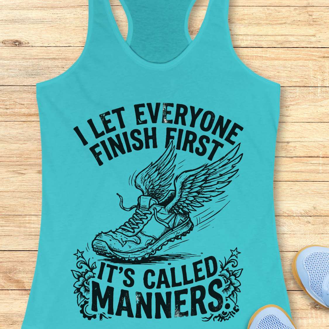 Turquoise tank top with black graphic and text on a wooden surface