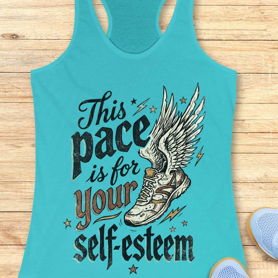 Turquoise tank top with motivational quote and shoe graphic on a wooden surface
