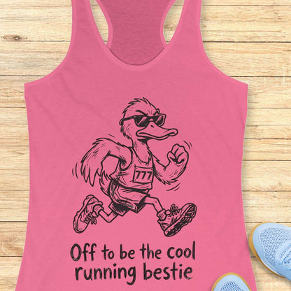 Pink tank top with a cartoon ostrich running and sunglasses on, text 'Off to be the cool running bestie' on a wooden surface.