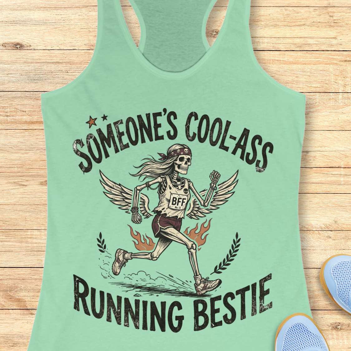 Light green tank top with skeleton design and text on a wooden surface