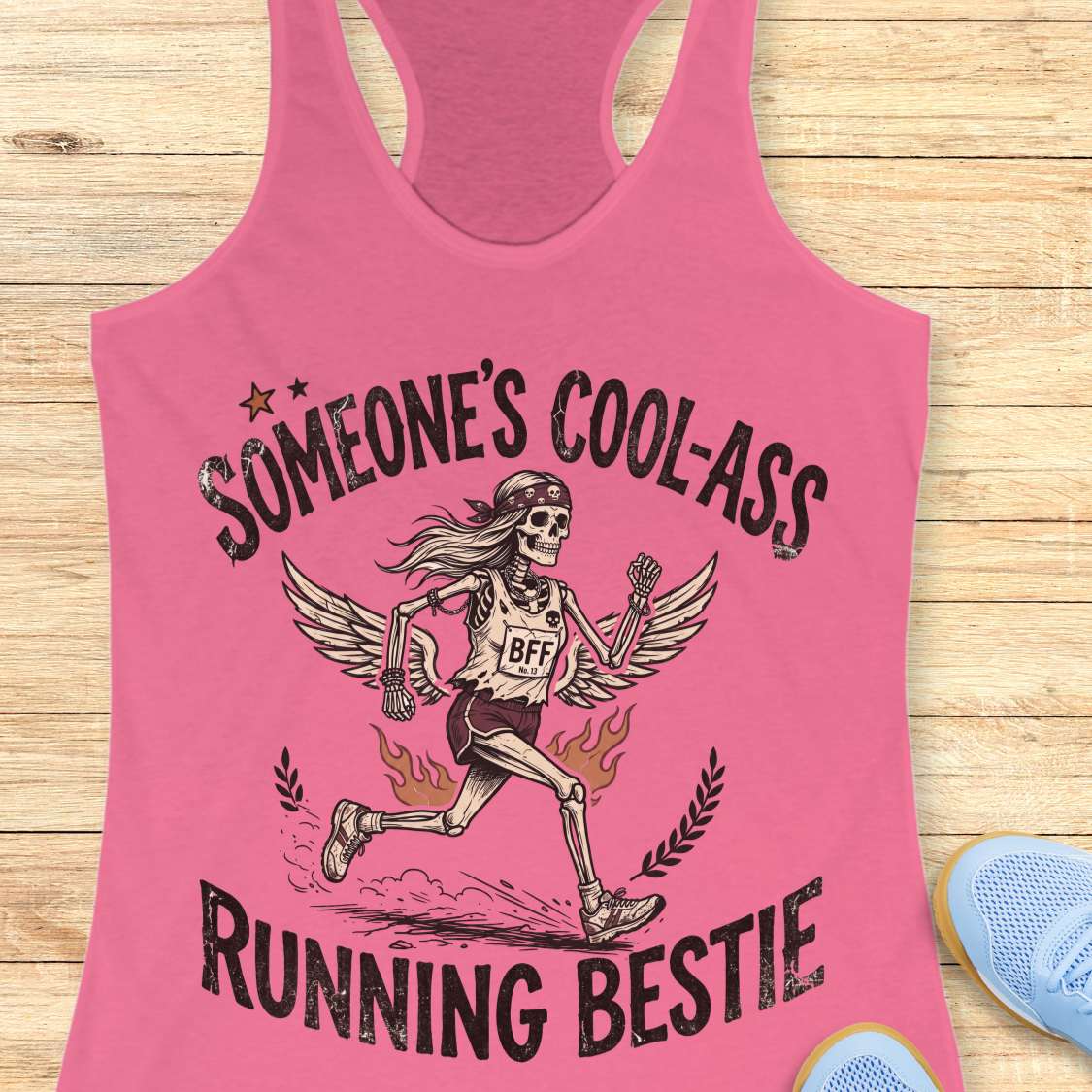 Pink tank top with skeleton design and text on a wooden surface