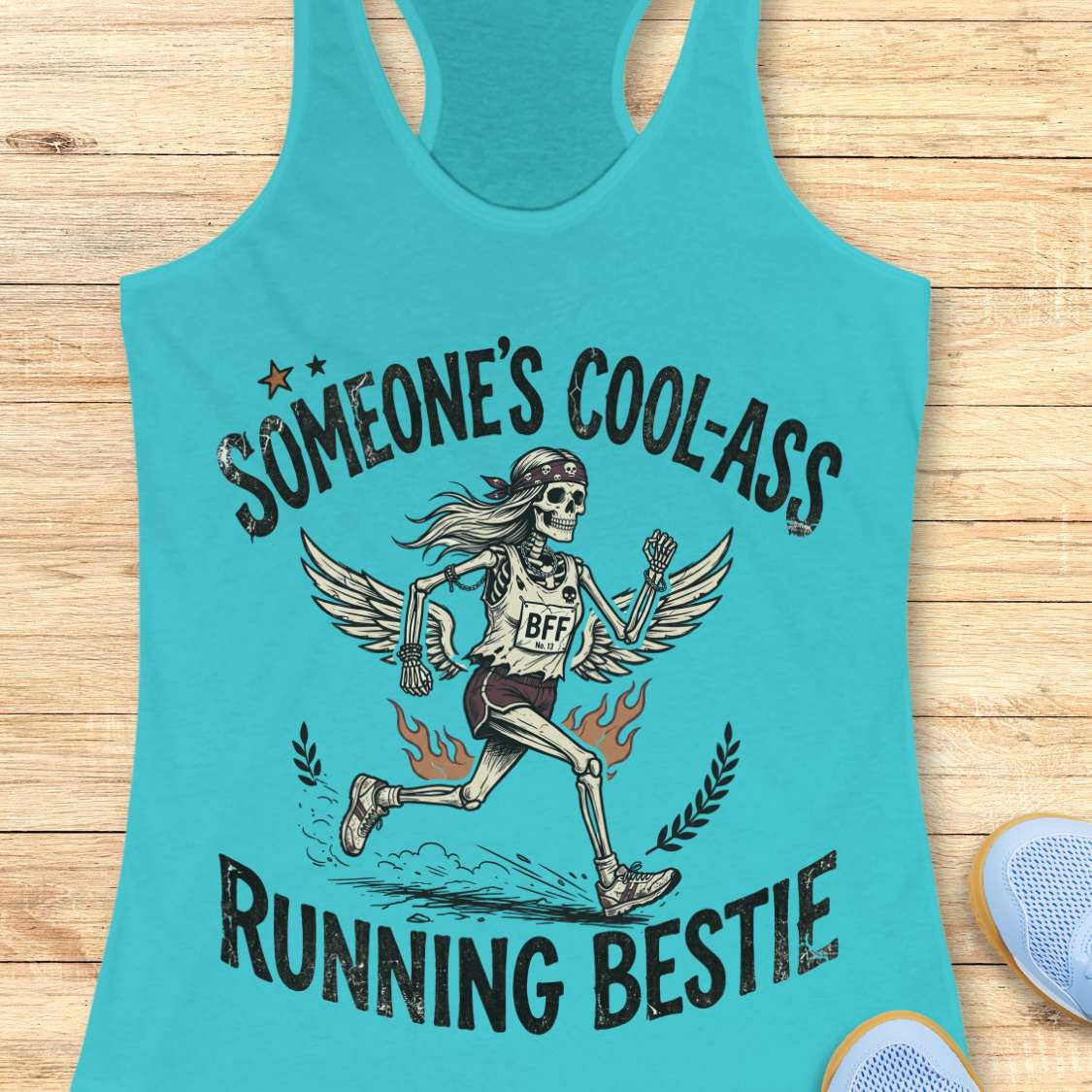 Turquoise tank top with skeleton graphic and text on a wooden surface