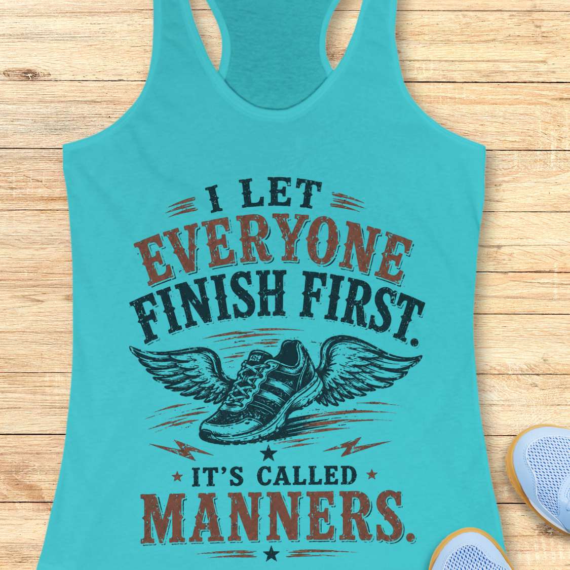 Turquoise tank top with motivational quote "I let everyone finish first. It's called manners." on a wooden surface