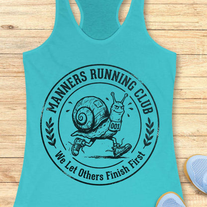 Turquoise tank top with 'Manners Running Club' graphic on a wooden surface